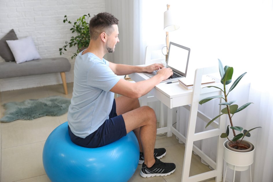 Muž, ktorý pracuje pri počítači a sedí na fit lopte